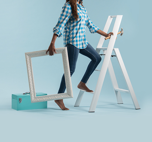 Artistic imagery of woman climbing up a ladder, holding a picture frame